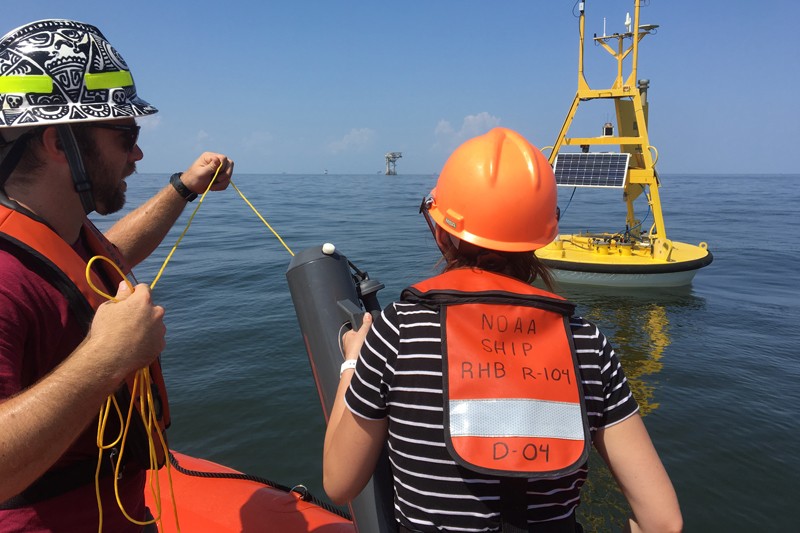 Scientists from NOAA’s Cooperative Institute for Marine and Atmospheric Studies (CIMAS) prepare to collect a water sample near an ocean acidification buoy in the Gulf of Mexico with an oil platform in the background. Credit: NOAA