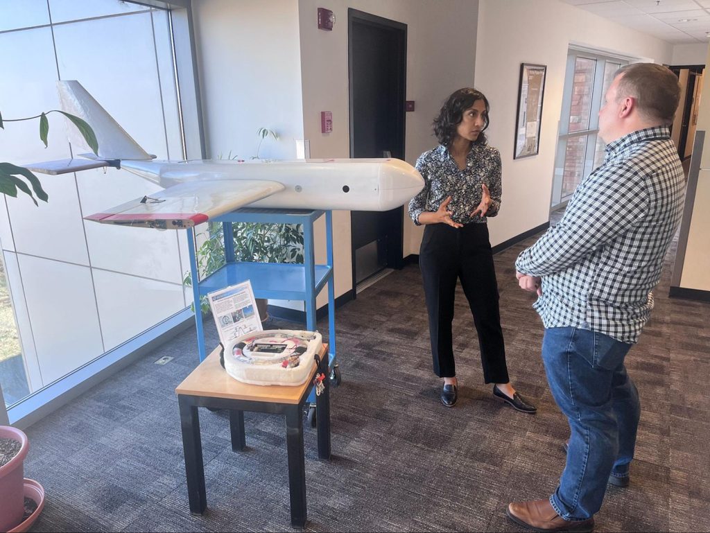 Parikha and Wayne talking while standing next to a model of a plane