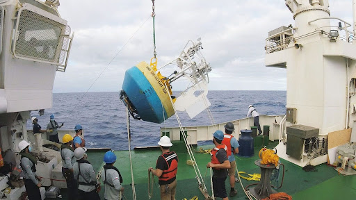 Scientists and crew members deploy a NOAA buoy in the Pacific Ocean to collect ocean and climate data. 