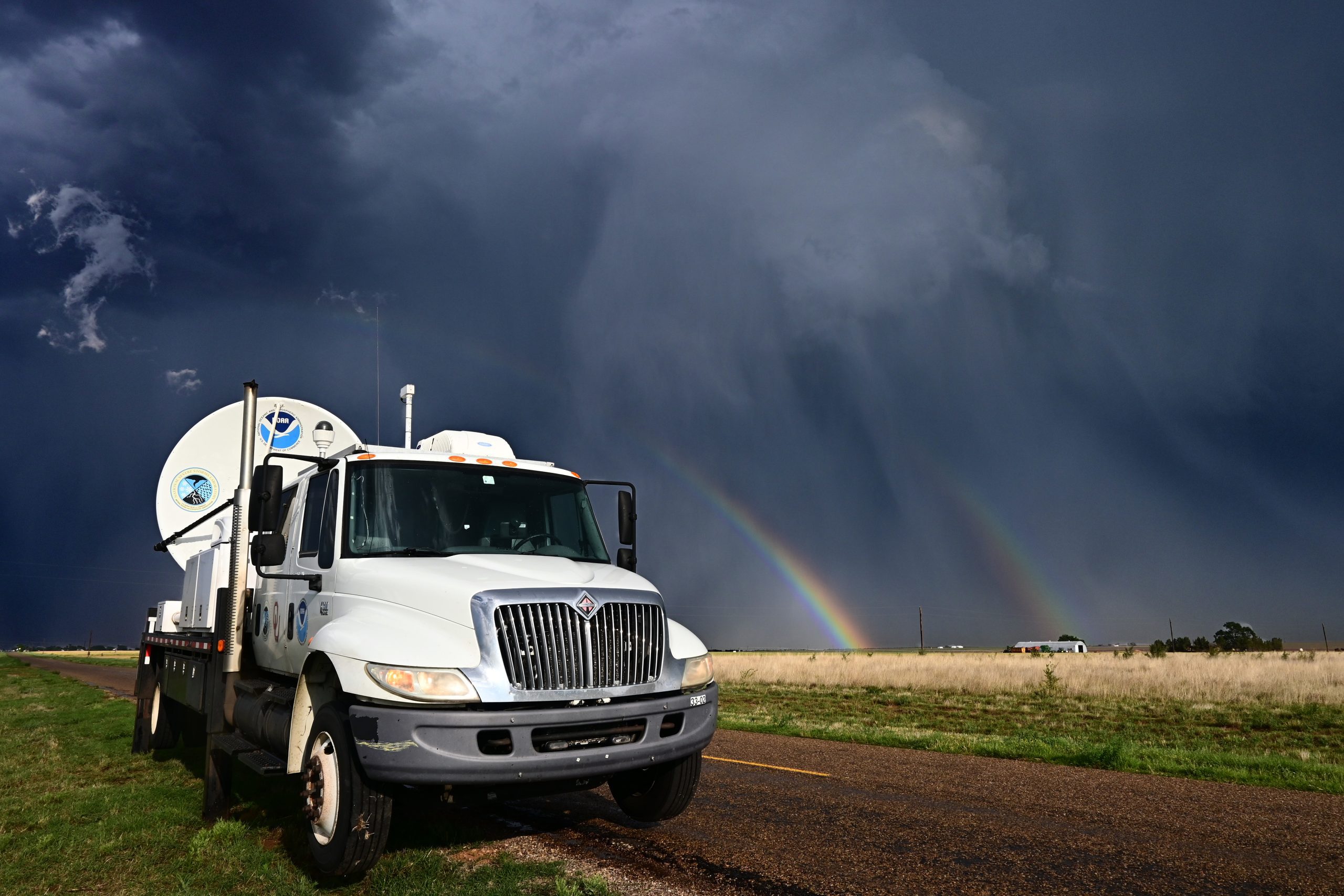 Mobile radar vehicle from NOAA NSSL with rainbows and stormy skies in the background.