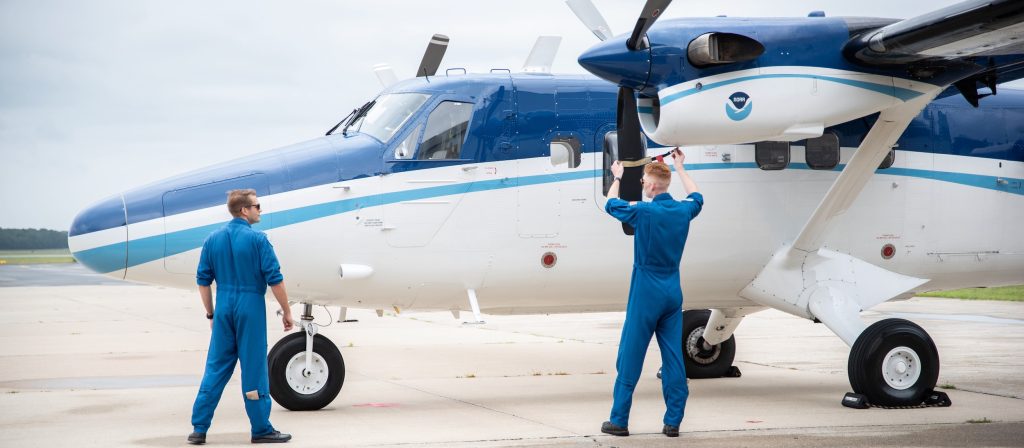 A photo of two NOAA pilots inspecting a Twin Otter research aircraft.