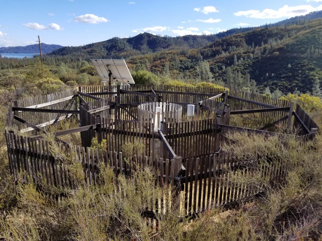 A set of field instruments is surrounded by wooden fencing in a grassy field.