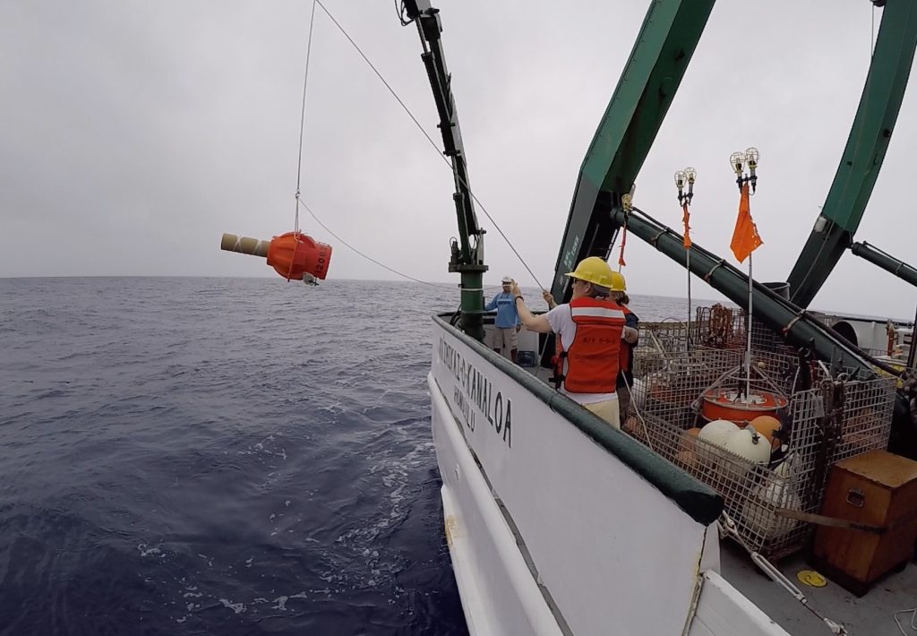 Scientists pitch a ocean float from a research vessel into the ocean.